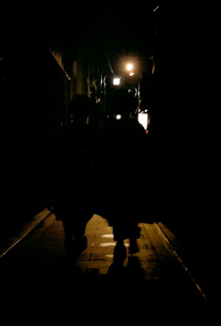 Deux maïkos marchent dans une ruelle du quartier de Gion, la nuit.