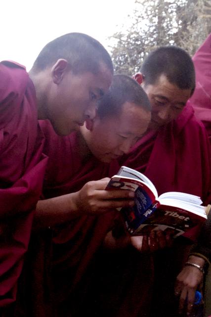 Des moines de Shigatsé s'intéresse à notre guide de voyage.