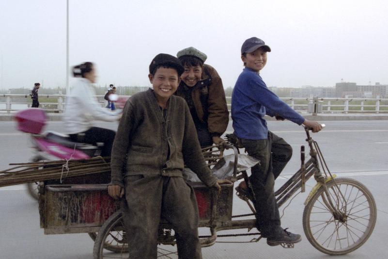 Des enfants transportent des matériaux sur un tricycle.