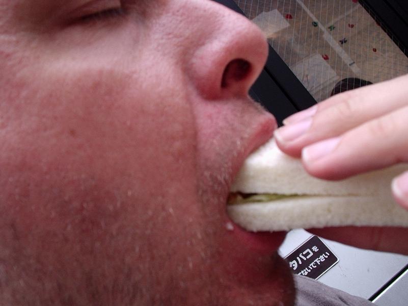 Un homme mange un sandwich avec appétit.